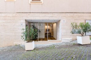 Entrada d'un edifici amb una porta de vidre, amb els números 6 i 7, i plantes en testos a banda i banda.