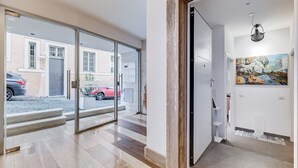 A modern interior with a glass door leading to a street view, a wooden door frame, and a colorful abstract painting on the wall. - BDC - The Left Loft in Trastevere (Roma)
