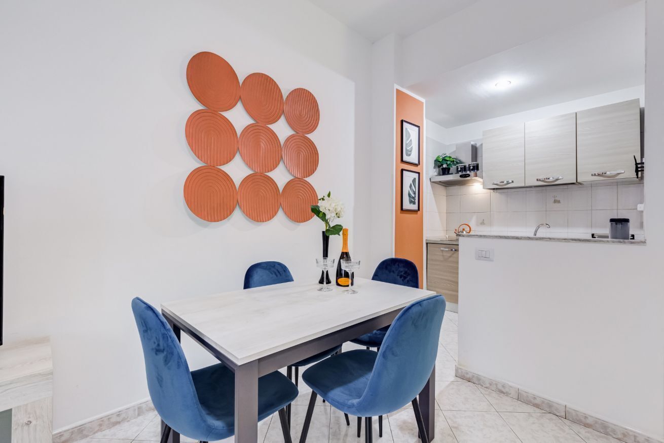 A modern dining area with a white table, blue chairs, and a decorative wall panel.