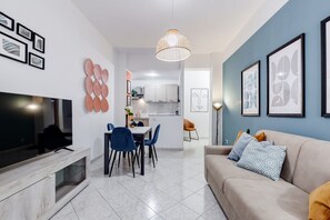 A modern living room with a TV, dining area, and kitchen in the background.