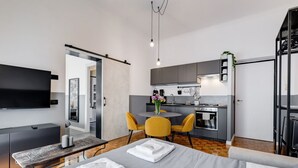 A modern hotel room with a bed, a desk, a dining area, and a kitchenette. - Classy Apartment | Auditorium & Villa Borghese (Roma)