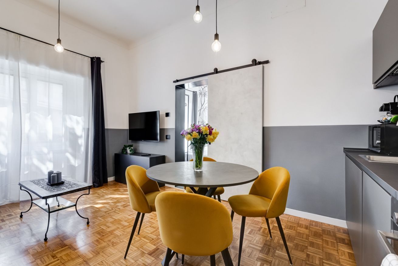 Una cocina moderna con comedor, suelo de madera y un ventanal con cortinas.