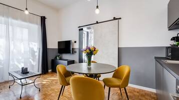Una cocina moderna con comedor, suelo de madera y un ventanal con cortinas.