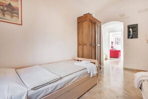 A single bed with a wooden headboard, a white wall, and a framed picture.