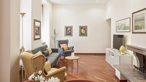 Un salon comprenant un canapé, des fauteuils, une table basse, une cheminée et des œuvres d’art accrochées aux murs.