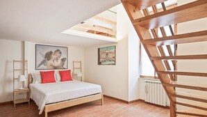 Une chambre à coucher avec un lit en bois, une lucarne, un radiateur et un tableau accroché au mur.
