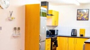 A modern kitchen with yellow cabinets, a black rug, and a wooden floor. - East London 1-bed Apt, Sleeps 2, With Parking (London)