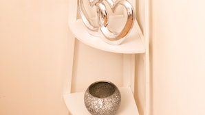 A white, curved, multi-tiered shelf unit with various decorative items. - East London 1-bed Apt, Sleeps 2, With Parking (London)