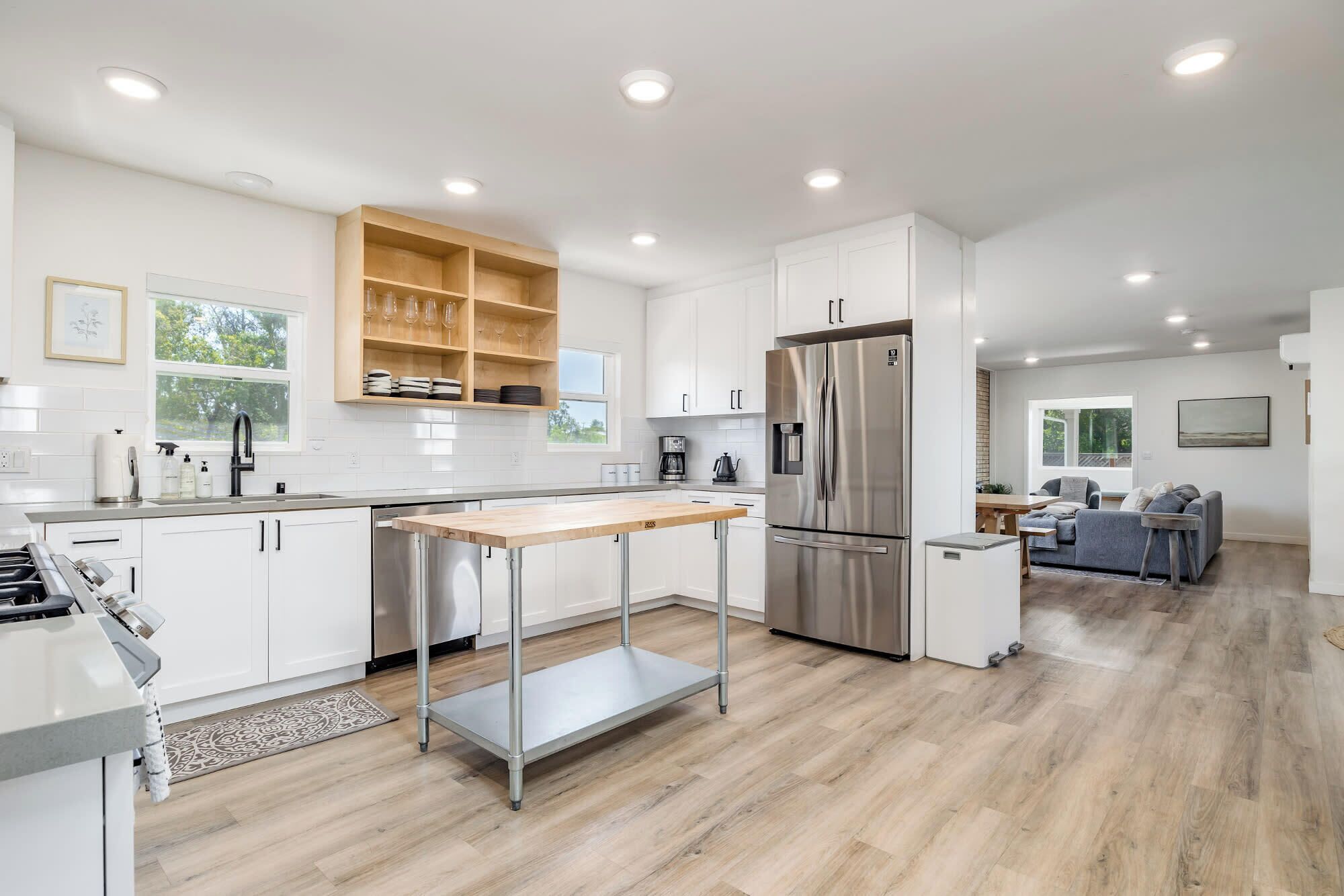 A modern kitchen with white cabinetry, a stainless steel refrigerator, and a wooden countertop.