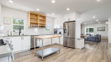 A modern kitchen with white cabinetry, a stainless steel refrigerator, and a wooden countertop.