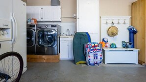 A compact laundry area with a washing machine, dryer, and a small sink. - Pleasure Point Getaway with hot tub, dog friendly! (Santa Cruz)