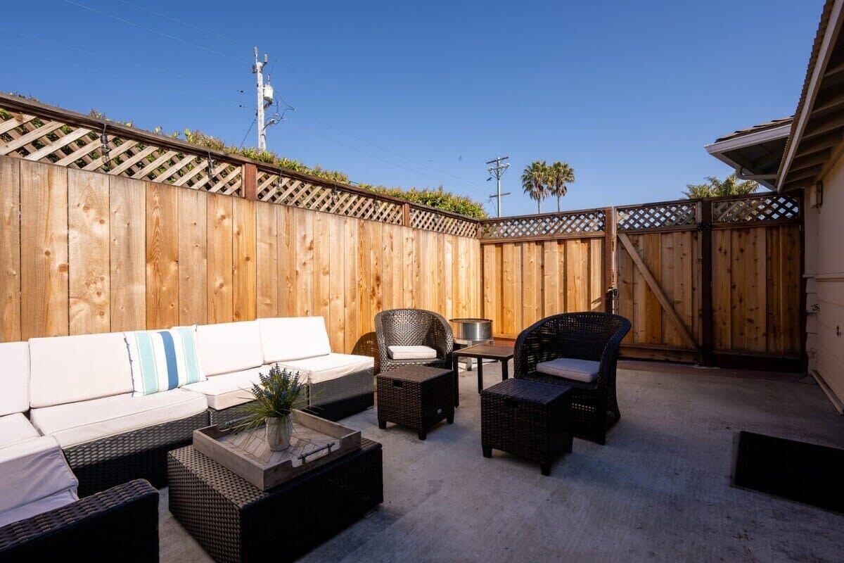 A patio with a wooden fence, outdoor furniture, and a clear sky.