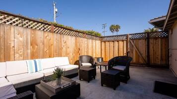 A patio with a wooden fence, outdoor furniture, and a clear sky.