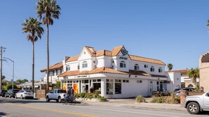 A two-story building with a white facade and red-tiled roof, featuring a storefront with a sign that reads 'CRIP CURL'. - Pleasure Point Getaway with hot tub, dog friendly! (Santa Cruz)