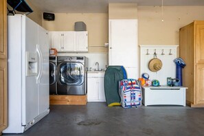 Une cuisine compacte équipée d’un réfrigérateur, d’un lave-linge et d’un petit plan de travail.