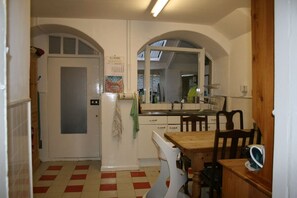 Compact kitchen area with a dining table and chairs, featuring a refrigerator, sink, and window above the sink.