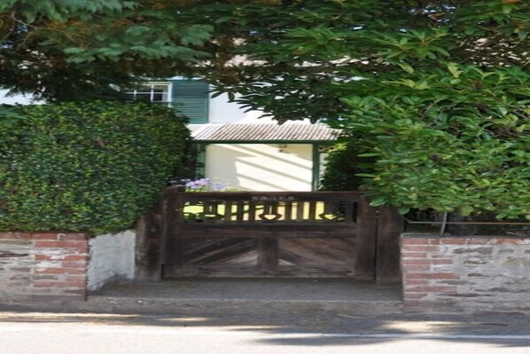 Secure entrance to a residence with a lush green hedge and a traditional building.