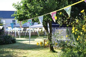 Guests can enjoy a tranquil outdoor setting with white tents and a lush tree.