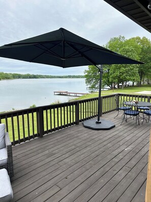 Une terrasse en bois avec une table et des chaises, donnant sur un lac.