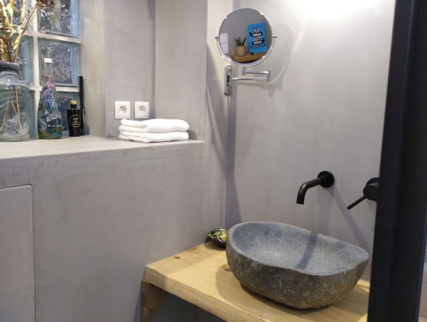 Une salle de bain avec un lavabo en pierre, un porte-serviettes et un miroir.