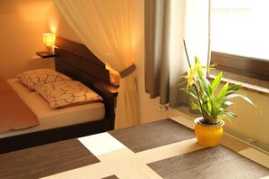 Relax in a cozy retreat with a neatly made bed, bedside table, and a potted plant.
