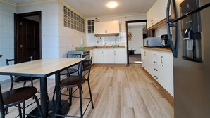 Una cocina moderna con armarios blancos, encimera de madera y refrigerador de acero inoxidable.