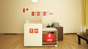 A reception area with a white desk, a yellow pendant light, and a wooden floor. - OYO Rooms 766 Delhi Airport (New Delhi)