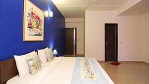 A hotel room with a bed, a blue wall, a framed picture, and a door. - OYO Rooms 766 Delhi Airport (New Delhi)
