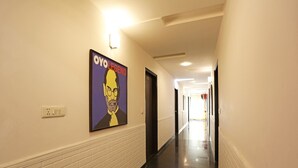 A hallway with white brick walls, a black floor, and a poster on the wall. - OYO Rooms 766 Delhi Airport (New Delhi)