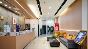 A hotel reception area with a wooden reception desk, a waiting area with a sofa and a coffee table, and a digital information kiosk. - Ripple Hotel (Sihong Renmin Road) (Sihong)