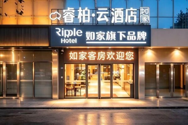 A hotel entrance with a sign reading 'Ripple Hotel' and another sign in a different language.