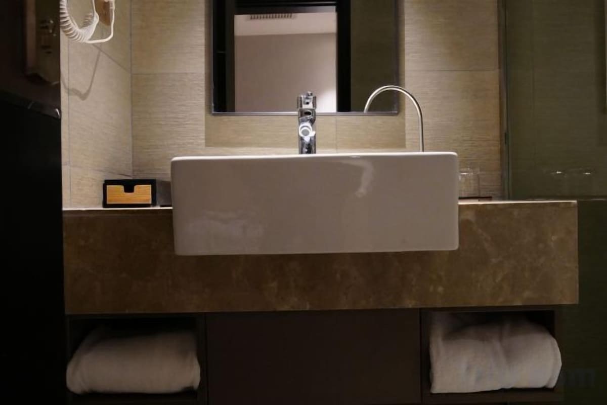 A bathroom with a sink, mirror, and towel storage.
