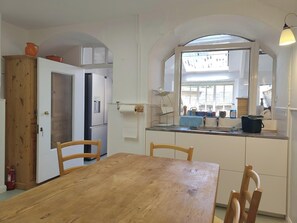 A kitchen with a wooden table, chairs, a refrigerator, and a window with a view. - Sages - Regency country villa in heart of Dolton (house and garden flat) (Dolton)