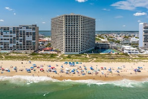 Et hotel ved stranden med flere etager, et poolområde og strandparasoller.