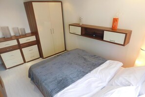Une chambre à coucher comprenant un lit, une armoire, une table de chevet et une étagère avec des objets décoratifs.