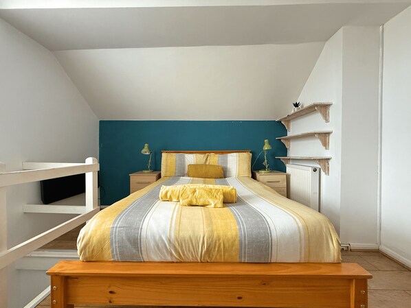 A bedroom with a bed, nightstands, a wooden bench, and a blue accent wall. - Spacious & Homely, 4 BR, Parking, Close to Centre (Lowfield)