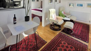 Um quarto moderno estilo loft com claraboia, área de refeições com mesa e cadeiras, e sala de estar com sofá e poltronas.