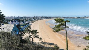 Une vue sur la côte, avec une plage de sable, un ciel bleu dégagé et une ville en arrière-plan.
