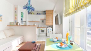 Un salon lumineux avec un canapé, une table basse et un coin repas où la table est mise pour le petit-déjeuner.