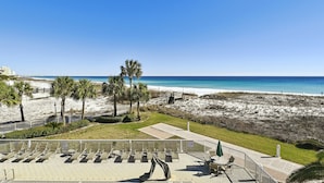 A beach view with a patio area, palm trees, and a sandy beach. - DOTG 304 - beautiful Gulf Front 2 BR with free beach service for 2 (Destin)