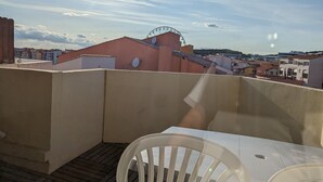 En takterrass med ett bord och stolar, ett pariserhjul i bakgrunden och en klar himmel.