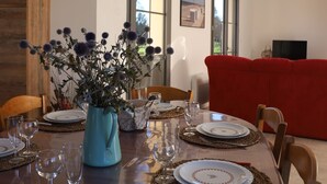 A dining table set with plates, cutlery, and a vase of flowers. - Les Gîtes de Sery Chez Michel (Bouillancourt-en-Séry)