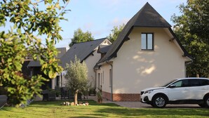 A modern house with a sloped roof, a well-maintained lawn, and a parked car. - Les Gîtes de Sery Chez Michel (Bouillancourt-en-Séry)