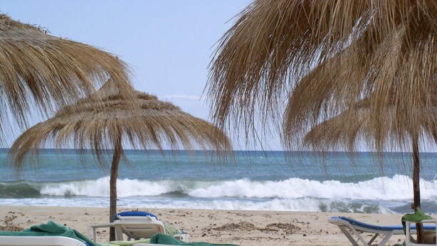 A beach with white lounge chairs and thatched umbrellas. - Top of Villa - Sea View - Private Beach Hammamet 8056, Tunisia (Hammamet)