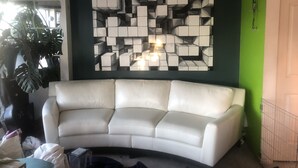 Ein Wohnzimmer mit einem weißen Ledersofa, einem Wandbild und einer grünen Akzentwand.