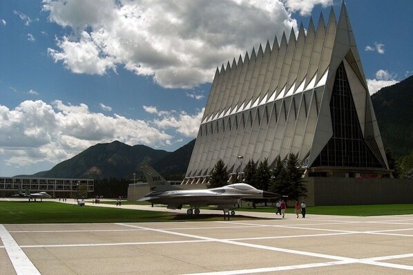 Un bâtiment moderne doté d’un toit triangulaire original et d’un avion de jet stationné devant.