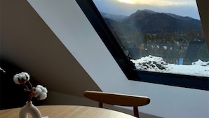 A room with a skylight, a vase with cotton, a plate with a croissant, and a view of snow-covered mountains. - Lipowy Dwór (Zakopane)