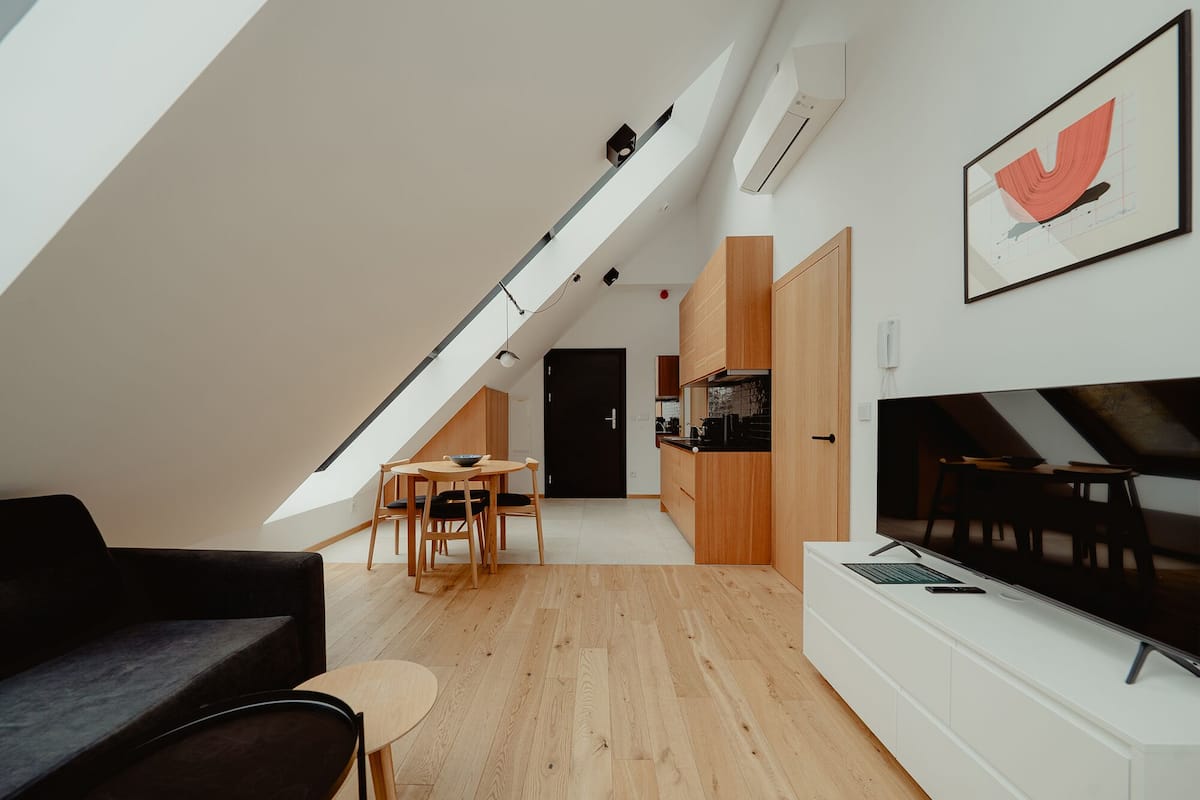 A modern loft apartment with a dining area, kitchen, and a large TV.
