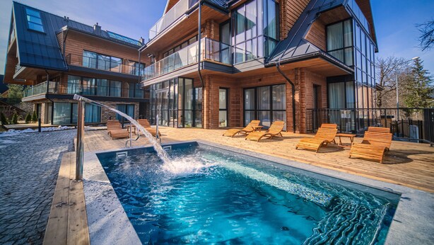 A modern two-story house with a swimming pool, wooden deck, and lounge chairs. - Lipowy Dwór (Zakopane)
