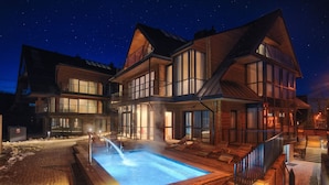 A large, multi-story wooden house with a heated outdoor pool and a staircase leading to a balcony. - Lipowy Dwór (Zakopane)